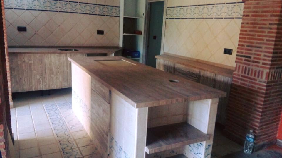 Cocina rústica con isla central y superficies de acabado pétreo