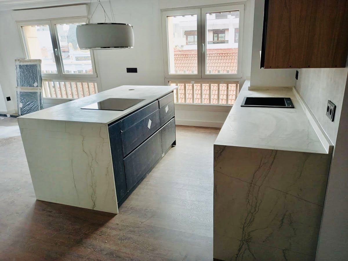 Cocina moderna con isla revestida en Neolith Mont Blanc y encimera porcelánica a medida.