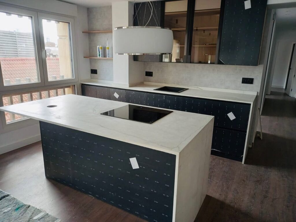Cocina moderna con isla revestida en Neolith Mont Blanc y encimera porcelánica a medida.