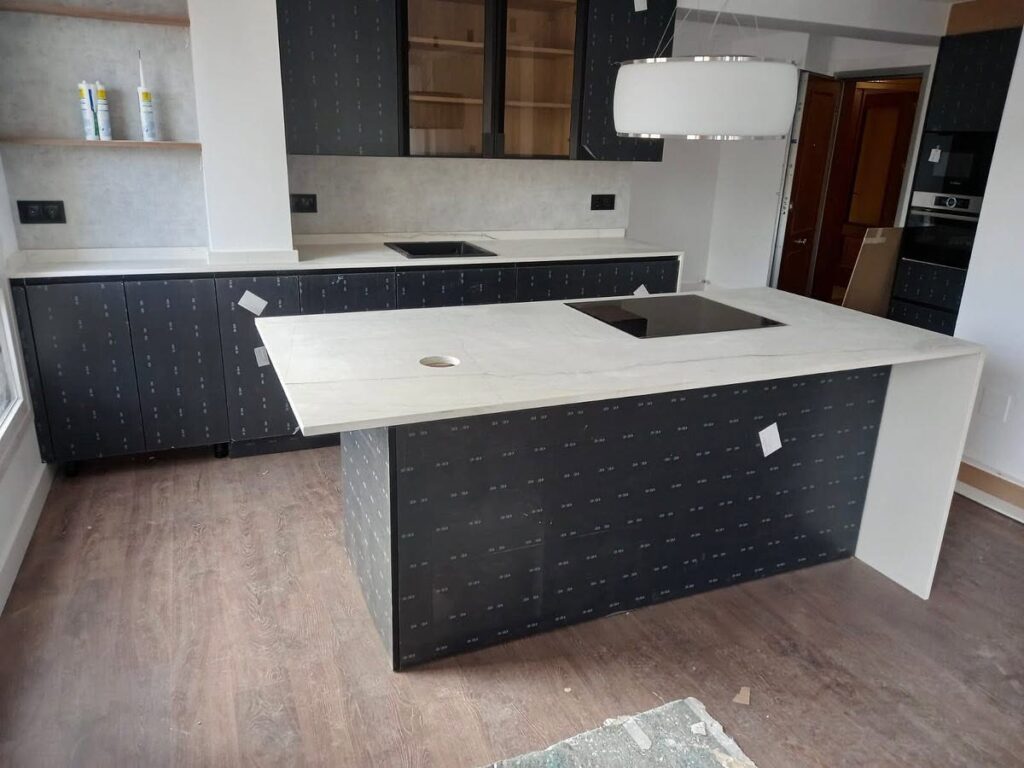Cocina moderna con isla revestida en Neolith Mont Blanc y encimera porcelánica a medida.